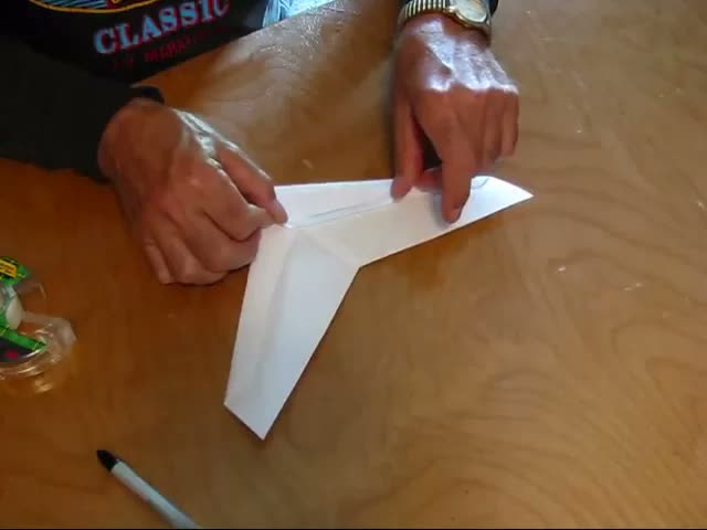 Mike Kelsey's hands taping the keel onto an OmniWing on a wooden table
